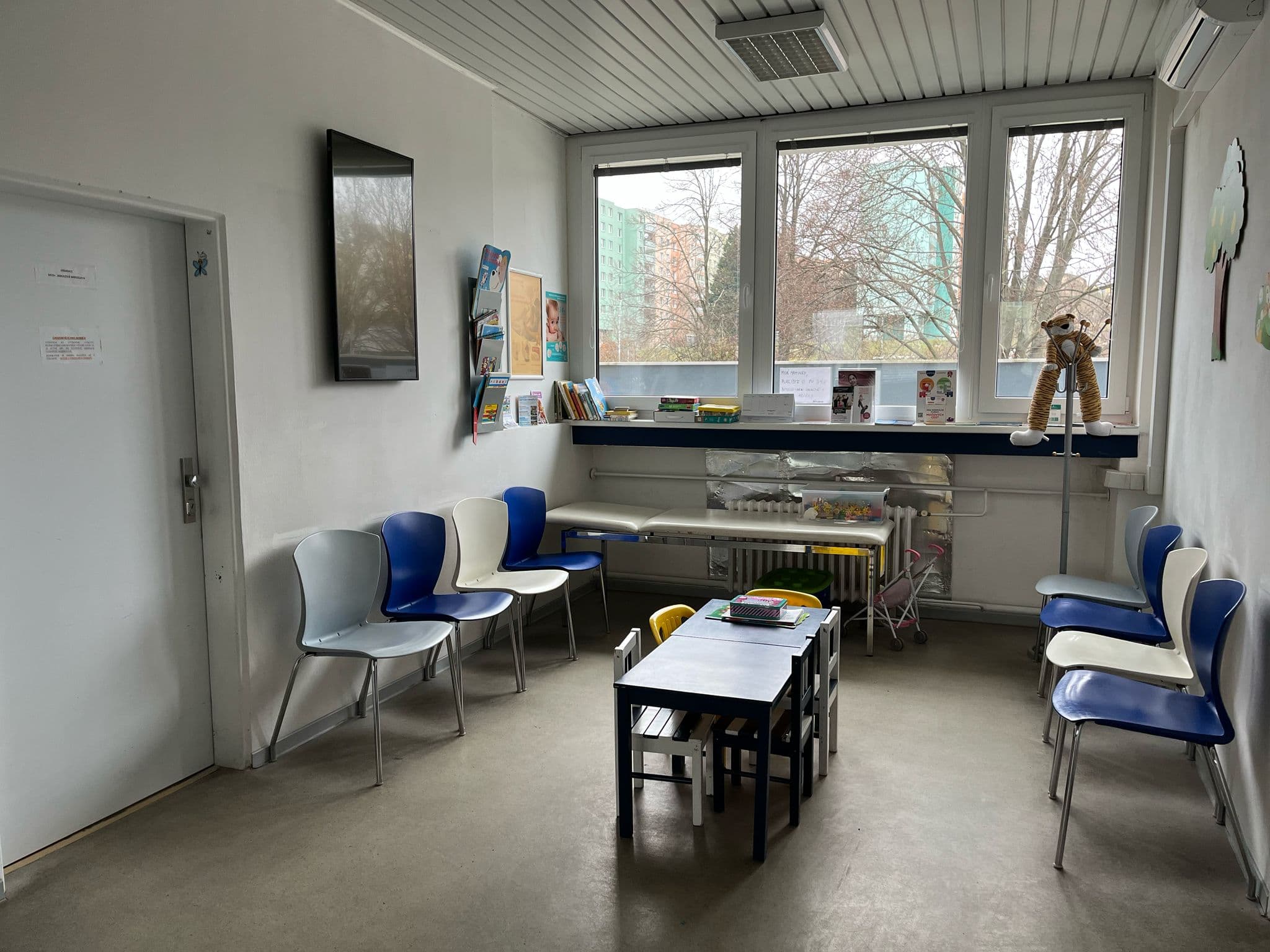 Prostor čekárny dětské ordinace s dětským stolečkem, žlutými židličkami a hračkami.